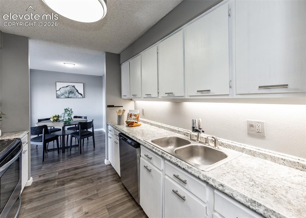 Image 2 of 12: Kitchen with white cabinetry, stainless steel appliances, speckled countert