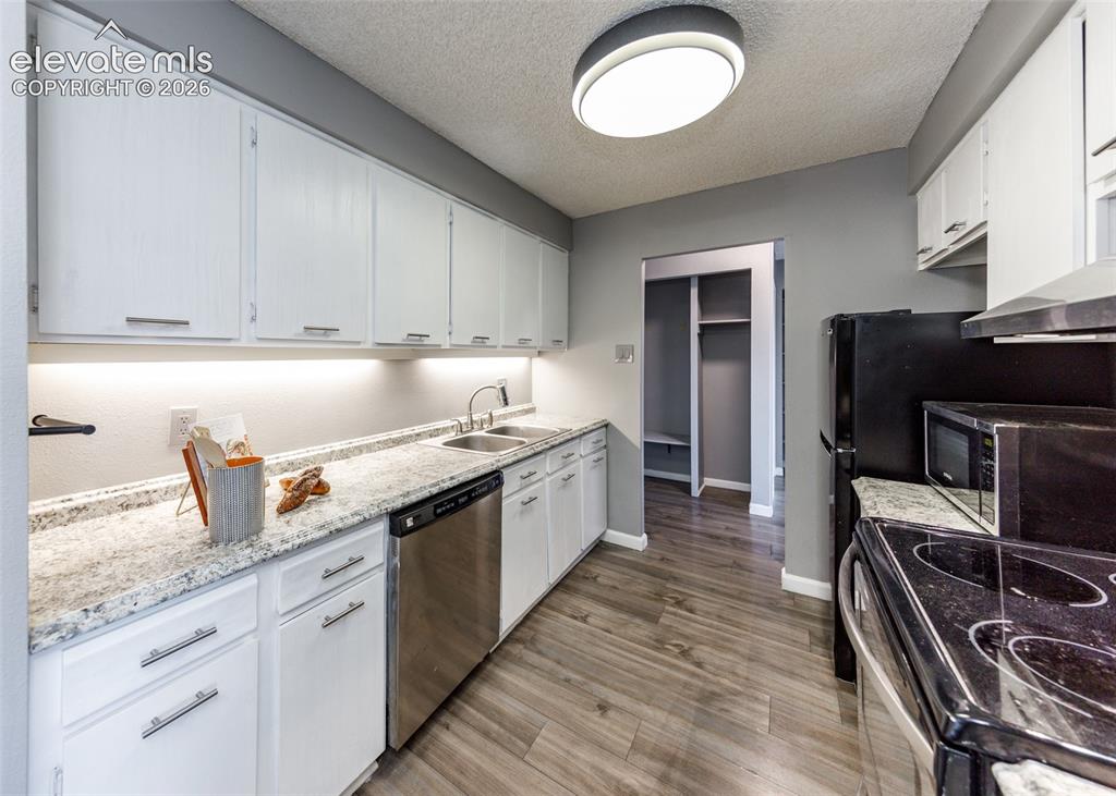 Image 3 of 12: Kitchen featuring white cabinetry, light-colored countertops, wood-finish f