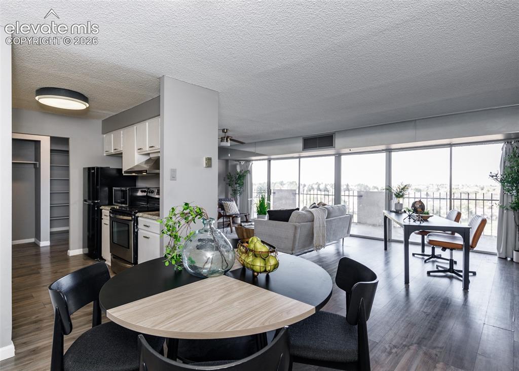 Image 7 of 12: Full-height windows, wood-finish flooring, white cabinetry, integrated rang