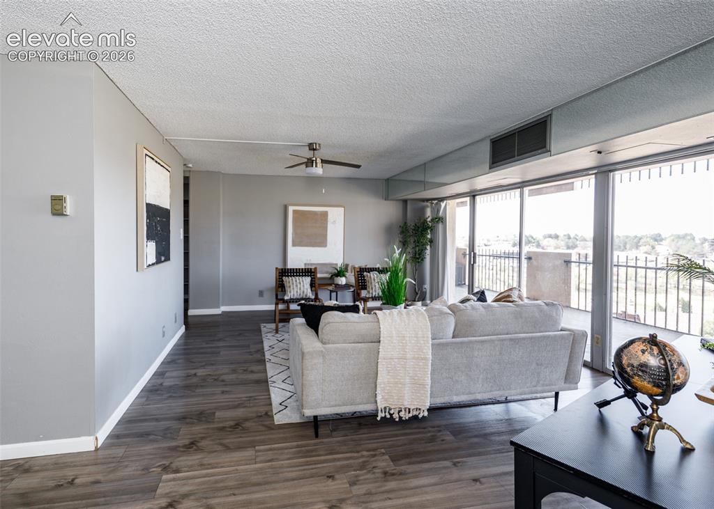 Image 8 of 12: Expansive living area featuring wood-finish flooring, ceiling fan, and slid