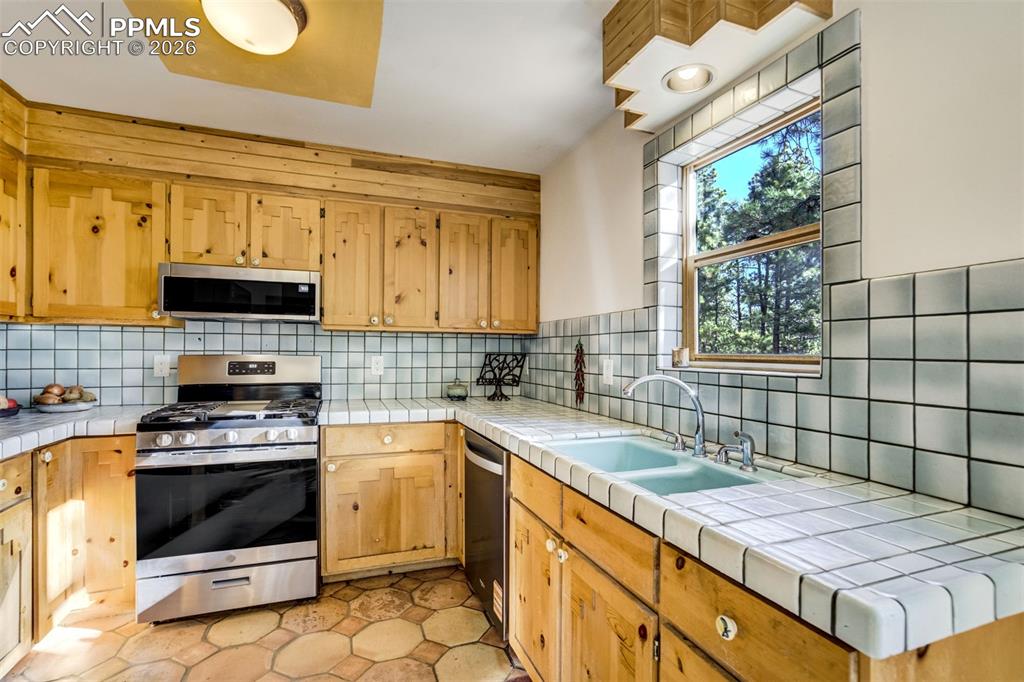 Image 12 of 45: Kitchen featuring stainless steel appliances, tile countertops, tile floors