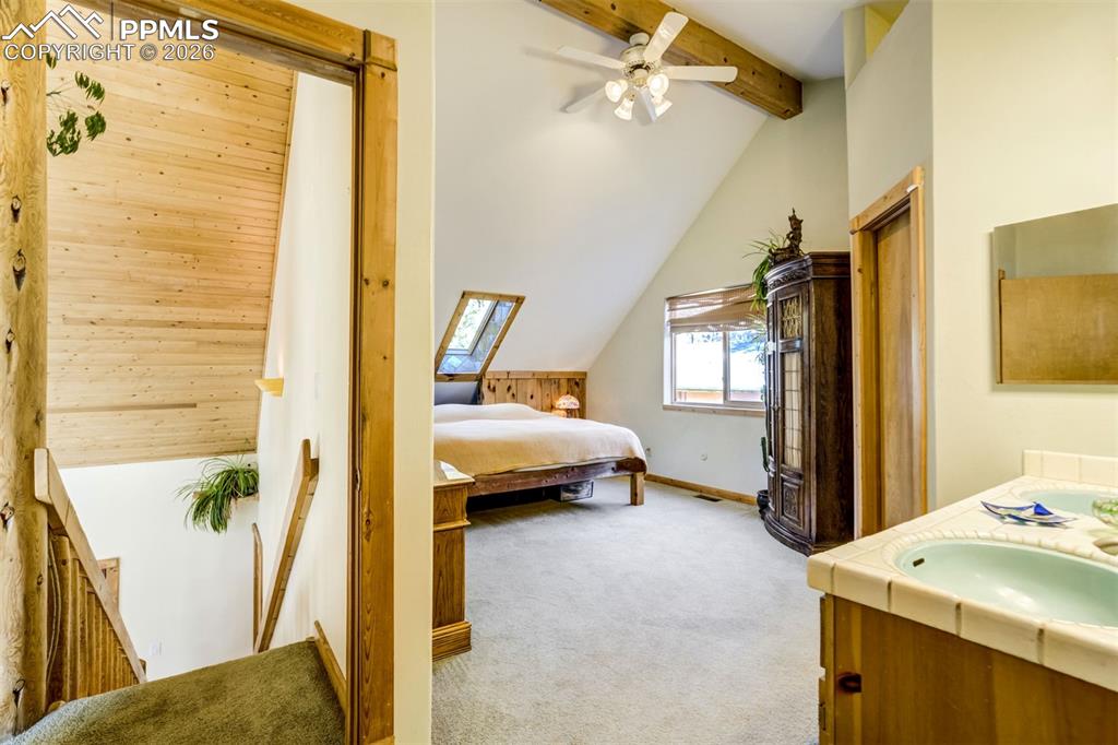 Image 22 of 45: Primary Bedroom featuring light carpet, vaulted ceiling, a ceiling fan, and