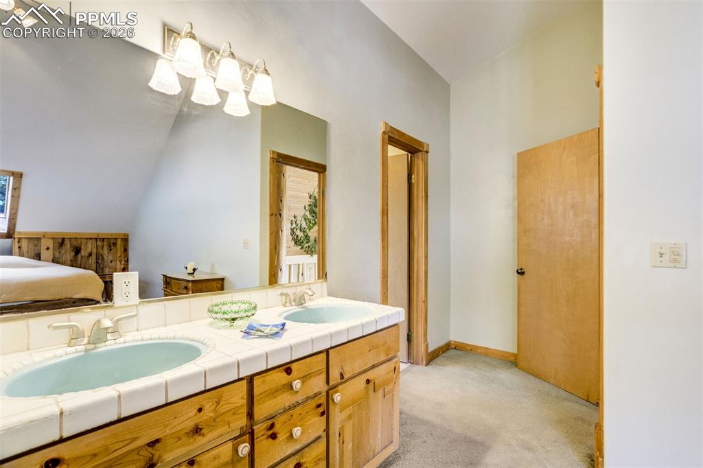 Image 24 of 45: Ensuite bathroom with light carpet, double vanity, and lofted ceiling