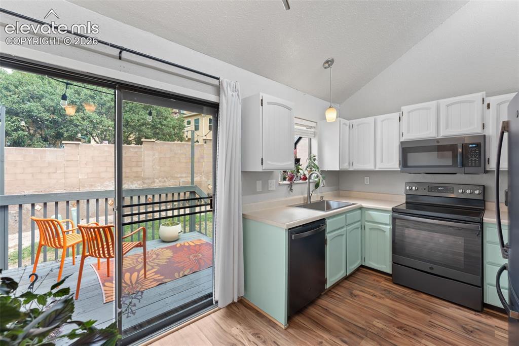 Image 11 of 28: Kitchen featuring wood-finish flooring, white upper cabinetry, and light gr