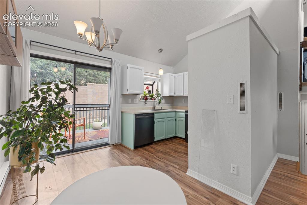 Image 12 of 28: Vaulted ceiling, wood-finish flooring, sliding glass door, kitchen with dis