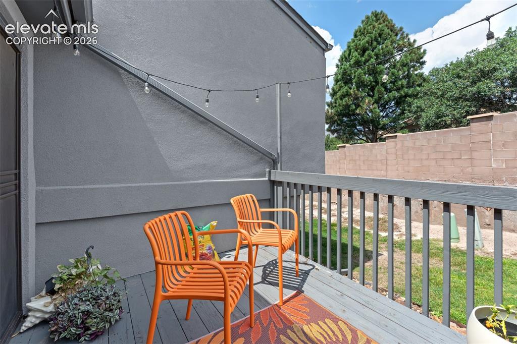 Image 14 of 28: Wood-finish deck with a painted railing, string lighting, and a partial pri
