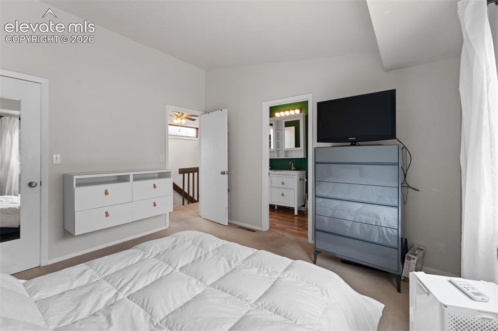 Image 19 of 28: Carpeted room with a wall-mounted dresser, an attached bathroom featuring a