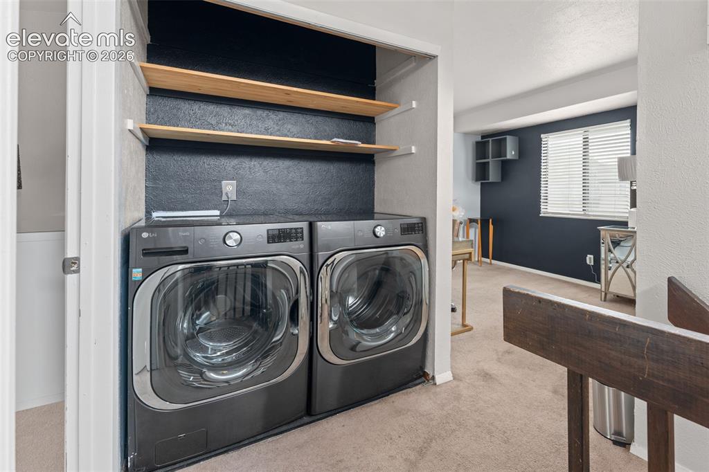 Image 23 of 28: Dedicated laundry area with built-in shelving, front-load washer and dryer,