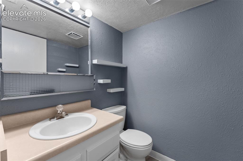 Image 24 of 28: White vanity with an integrated oval sink, three wall-mounted shelves, a mi