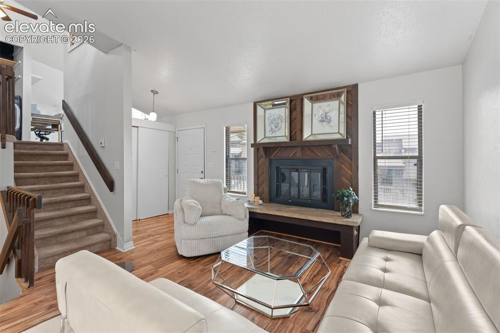 Image 5 of 28: Living area featuring wood-finish flooring, a fireplace with a wood-paneled