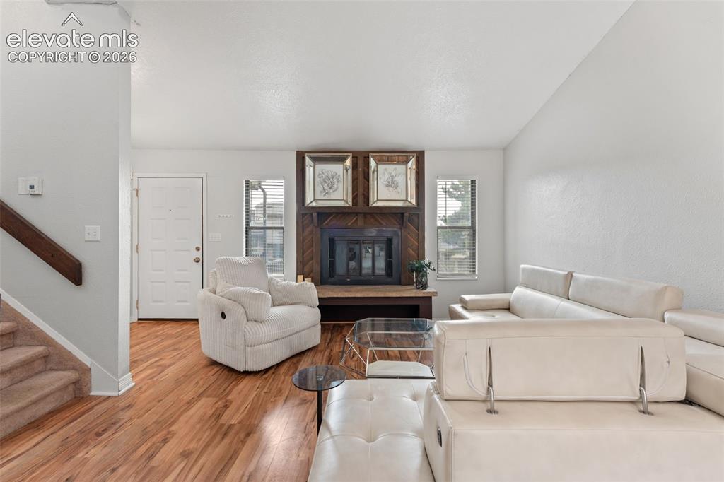 Image 6 of 28: Wood-finish flooring throughout, a fireplace with a wood-paneled surround,