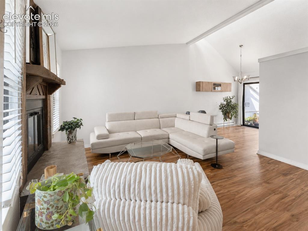 Image 8 of 28: Living area featuring wood-finish flooring, a fireplace with a stone hearth