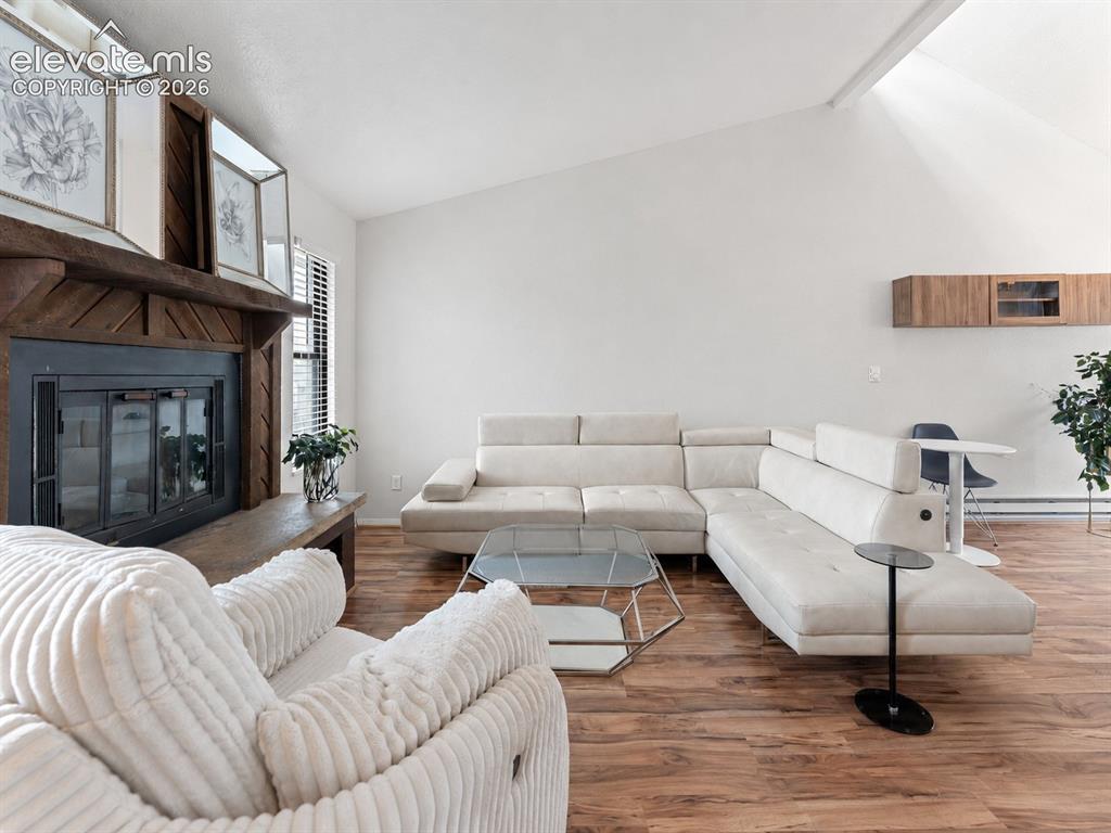 Image 9 of 28: Vaulted ceiling, wood-finish flooring, wood-clad fireplace, and built-in fl