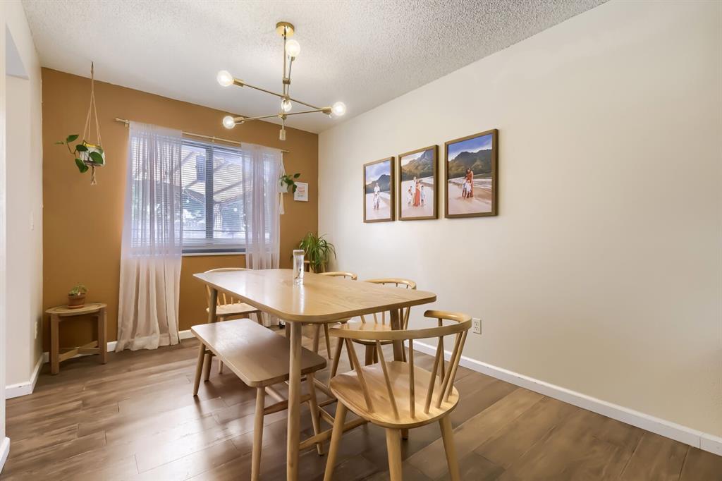 Image 10 of 22: Dining area featuring wood-finish flooring, a modern brass-finish chandelie