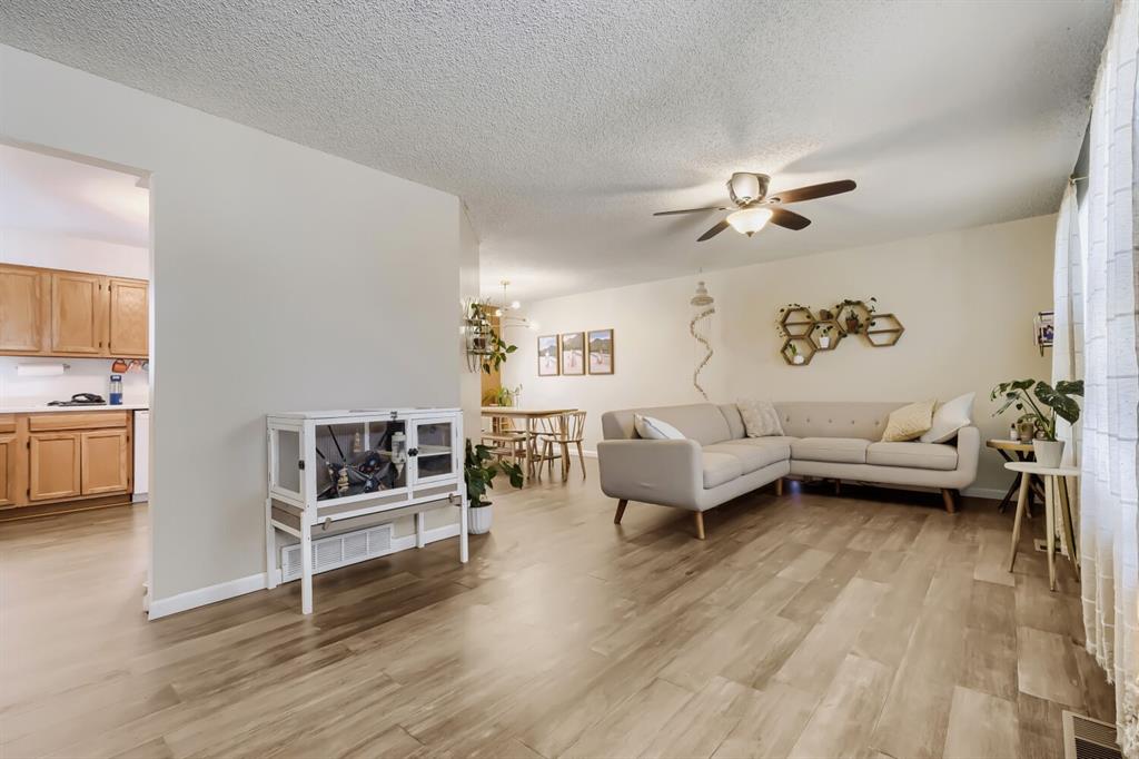 Image 12 of 22: Spacious living area featuring wood-finish flooring, a ceiling fan, and abu