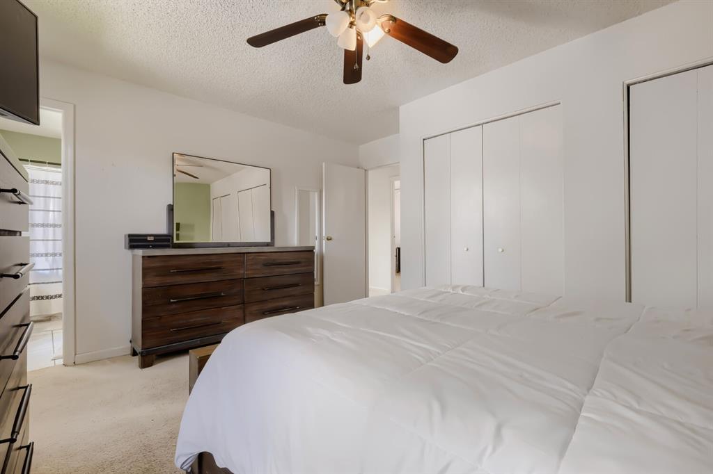 Image 14 of 22: Carpeted bedroom with a ceiling fan, dual bi-fold closets, and an entryway 