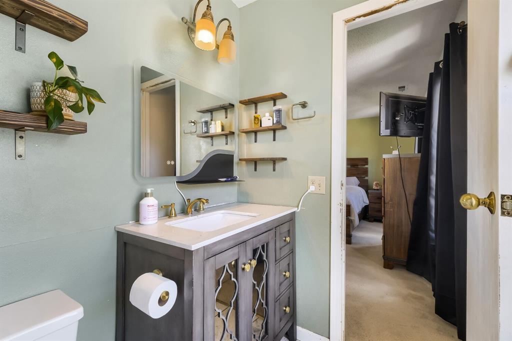 Image 17 of 22: Bathroom vanity featuring a quartz countertop, gold-tone faucet, and integr