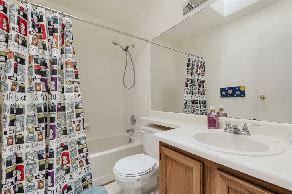 Image 19 of 22: Full bathroom featuring a single vanity with wood-finish cabinetry, a white