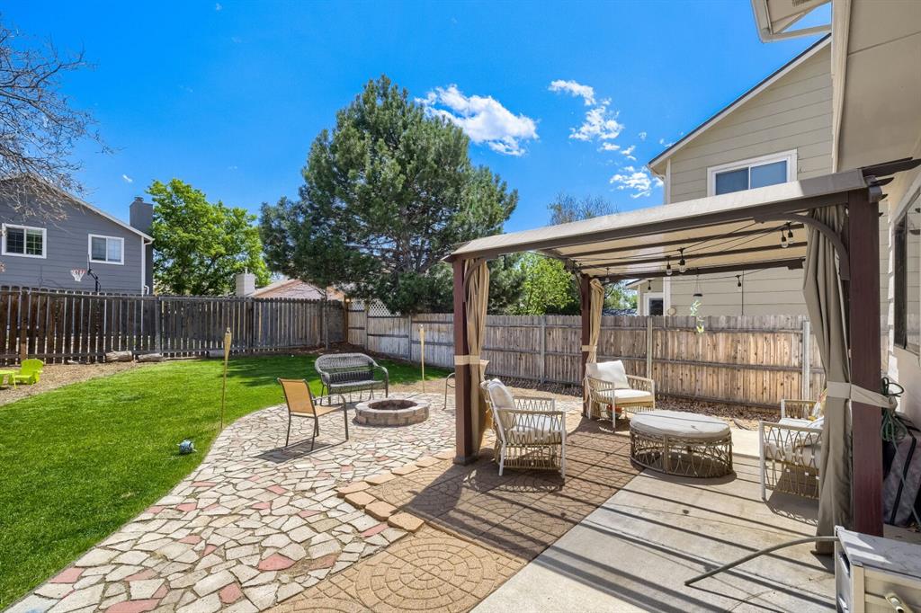 Image 22 of 22: Expansive backyard featuring a stone patio with a built-in fire pit, a sepa