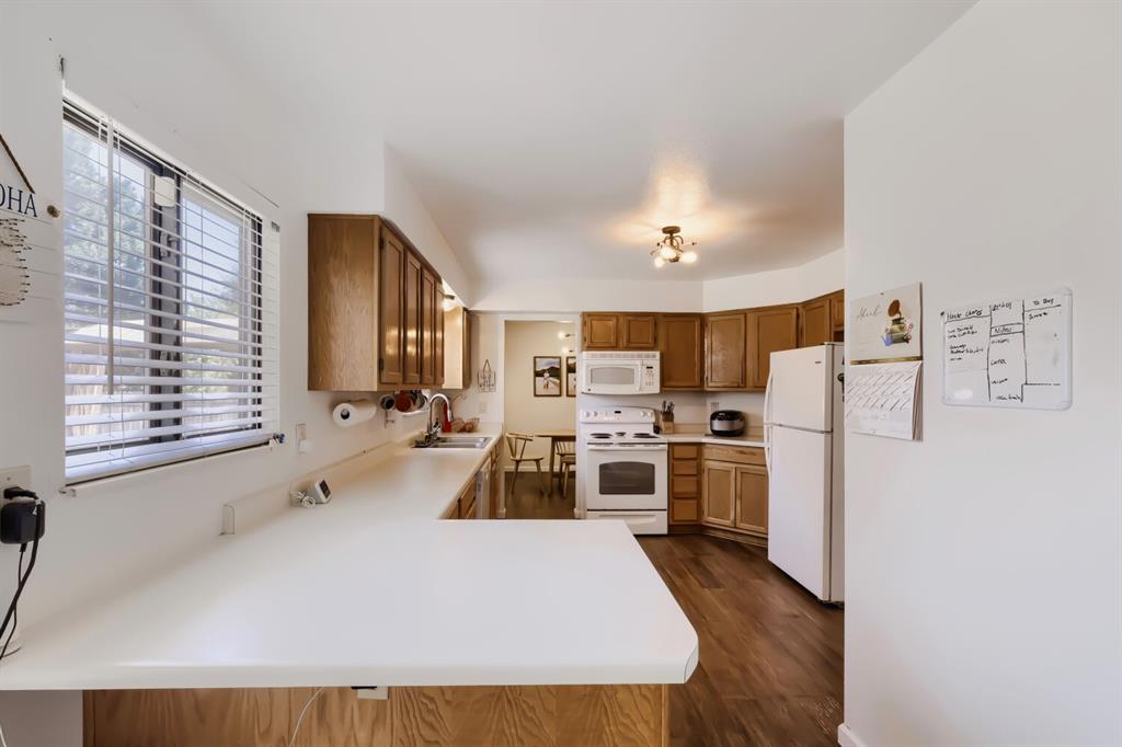 Image 7 of 22: Open-concept kitchen featuring wood cabinetry, white countertops, wood-fini