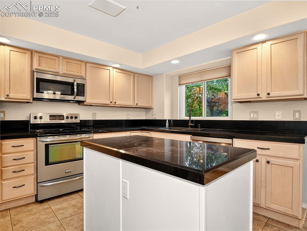 Image 10 of 27: Kitchen featuring light brown cabinetry, stainless steel appliances, and re
