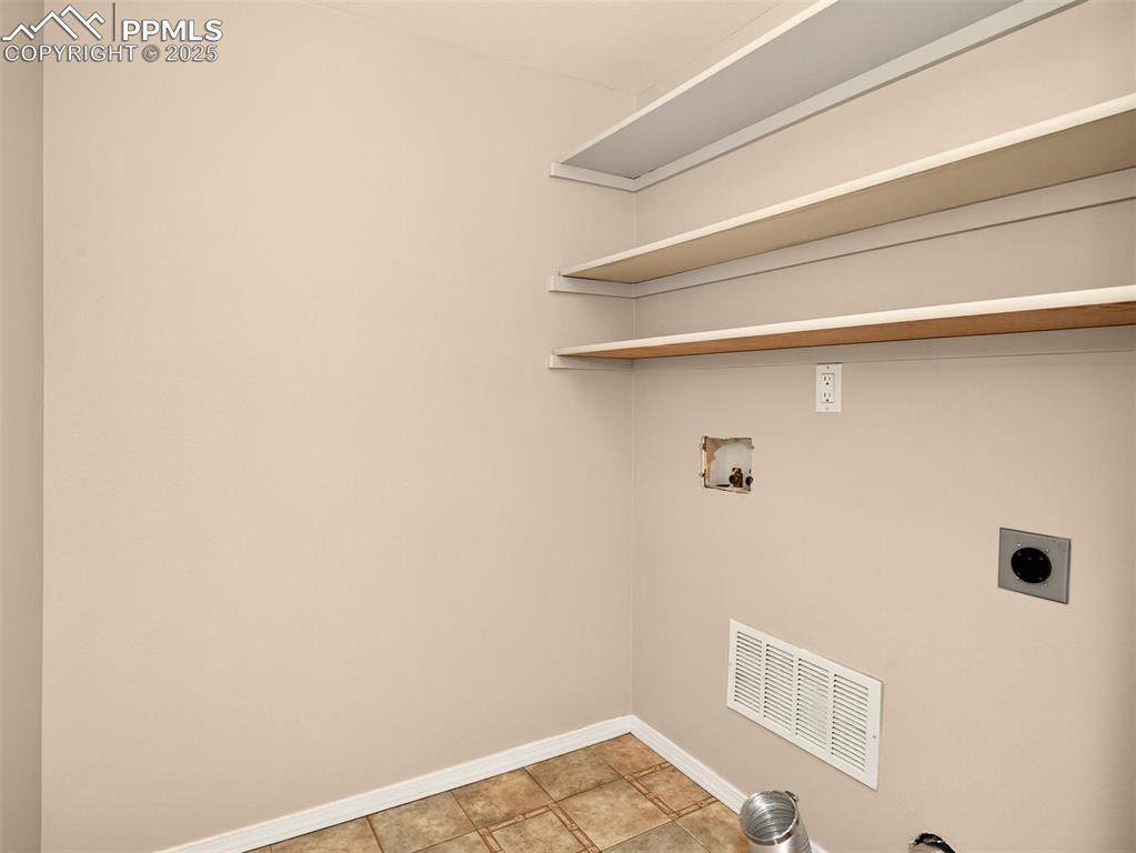 Image 12 of 27: Laundry area with hookup for a washing machine and light tile patterned flo
