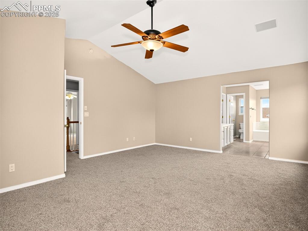 Image 14 of 27: Unfurnished bedroom with vaulted ceiling, light carpet, ensuite bathroom, a