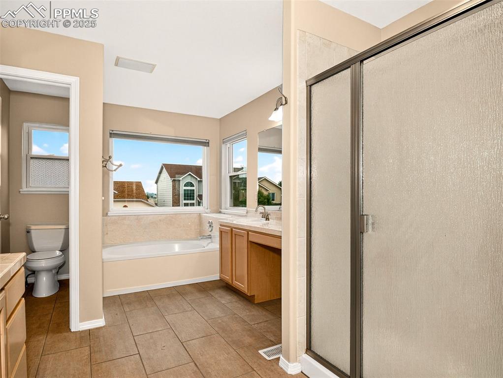 Image 15 of 27: Full bath with vanity, a stall shower, a garden tub, and light tile pattern