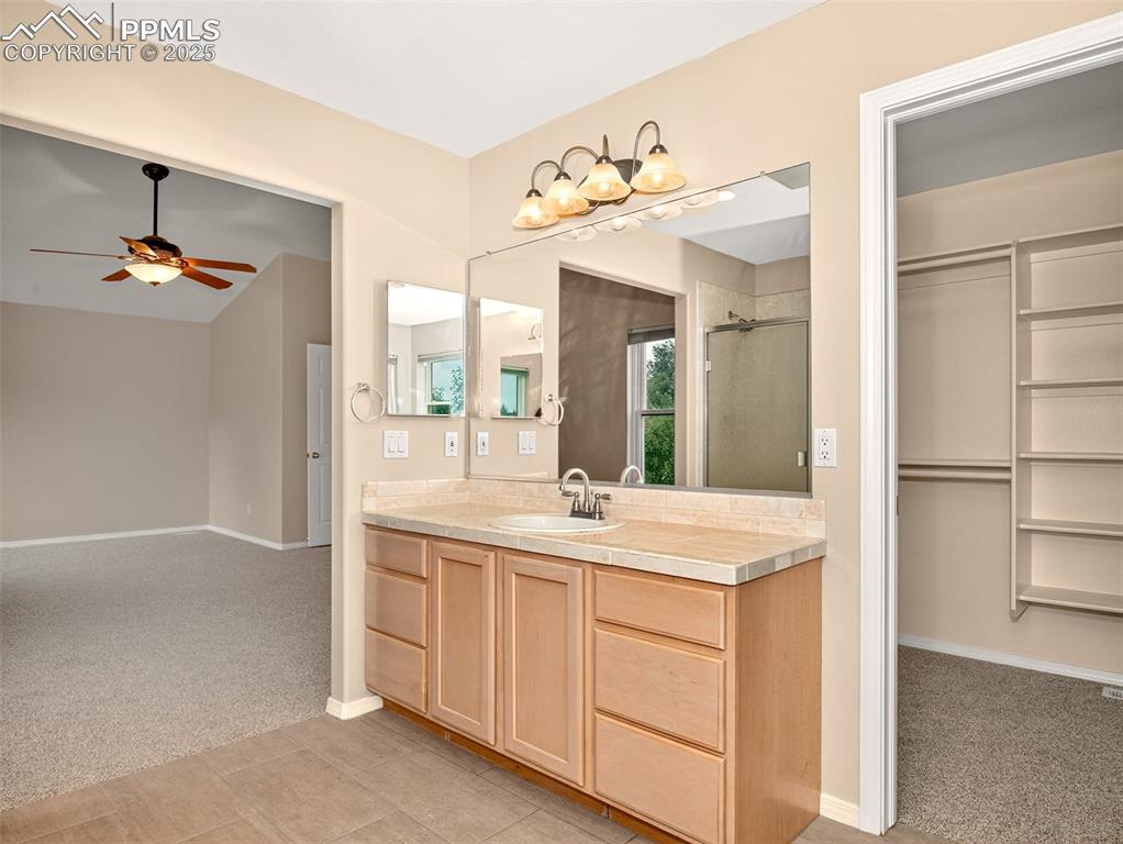 Image 16 of 27: Bathroom featuring vanity, a spacious closet, a shower, light tile patterne