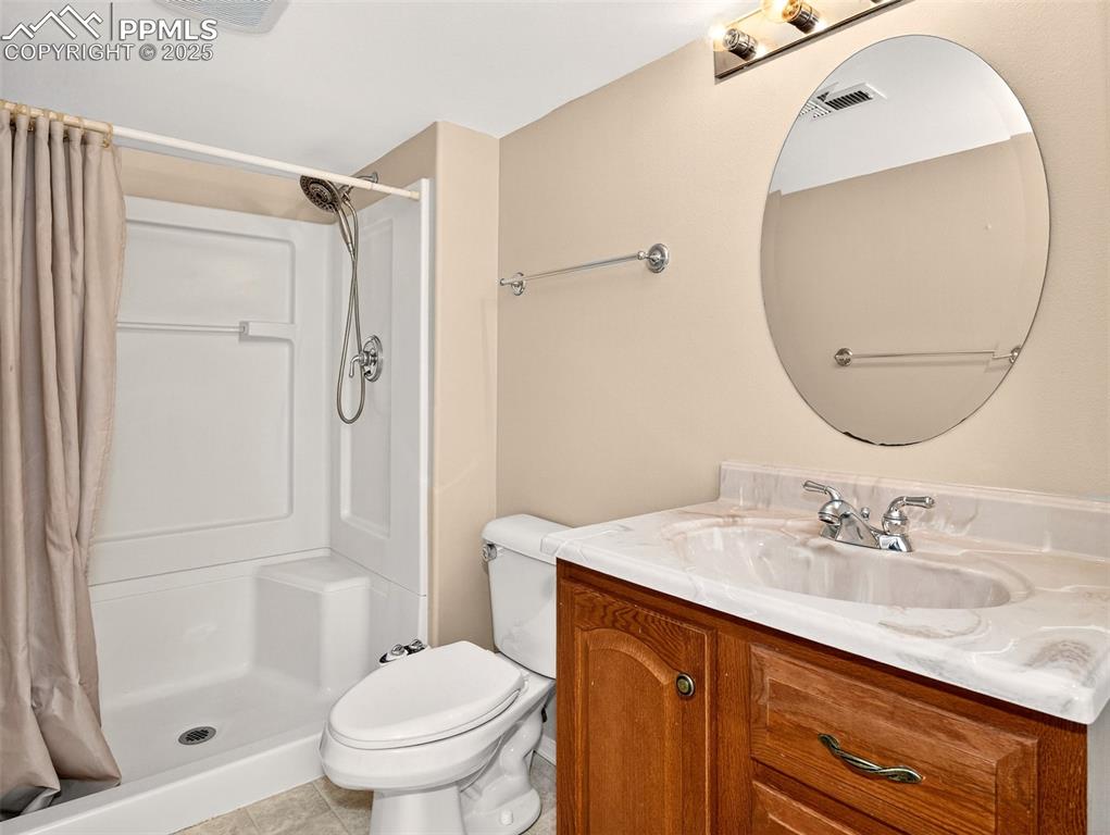 Image 24 of 27: Bathroom featuring vanity, light tile patterned floors, and a shower stall