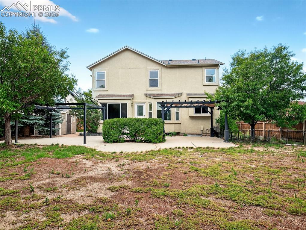 Image 26 of 27: Back of property featuring stucco siding, a pergola, a patio area, and a st