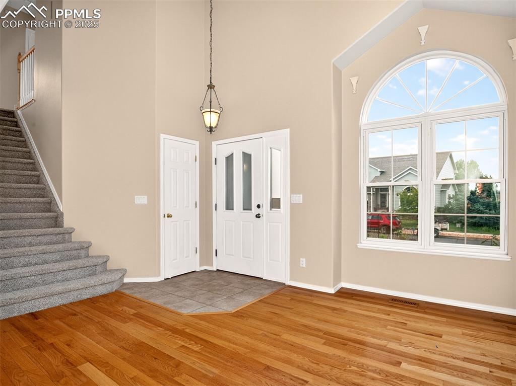 Image 4 of 27: Entryway with stairway, light wood-type flooring, and a high ceiling