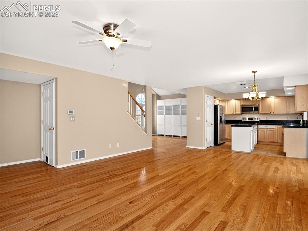 Image 6 of 27: Unfurnished living room with stairway, light wood-type flooring, ceiling fa