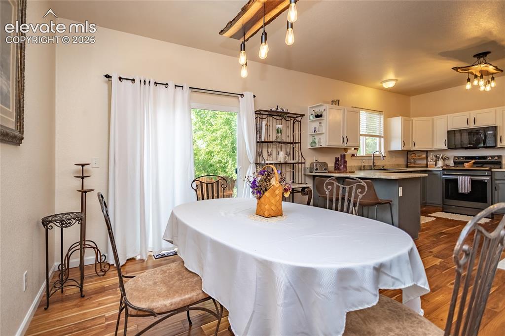 Image 11 of 44: Illuminated by a custom designer light fixture, this spacious dining area i