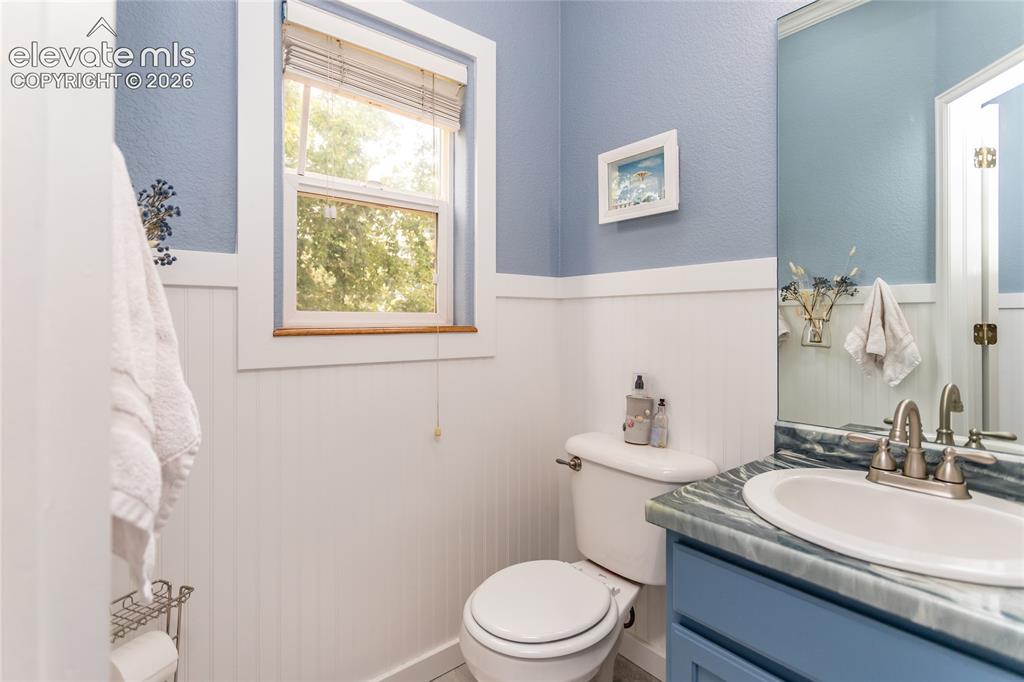 Image 20 of 44: The main-level powder room features charming cottage beadboard wainscoting 