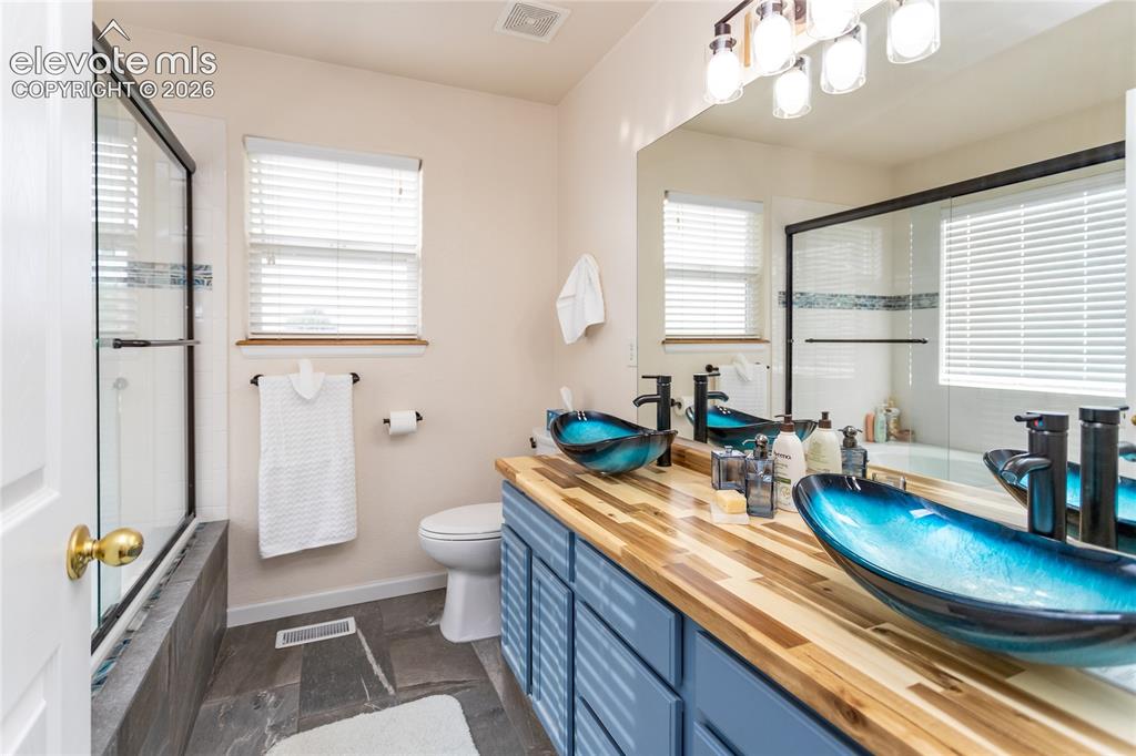 Image 28 of 44: The adjoined primary bathroom is a designer masterpiece, boasting custom wo