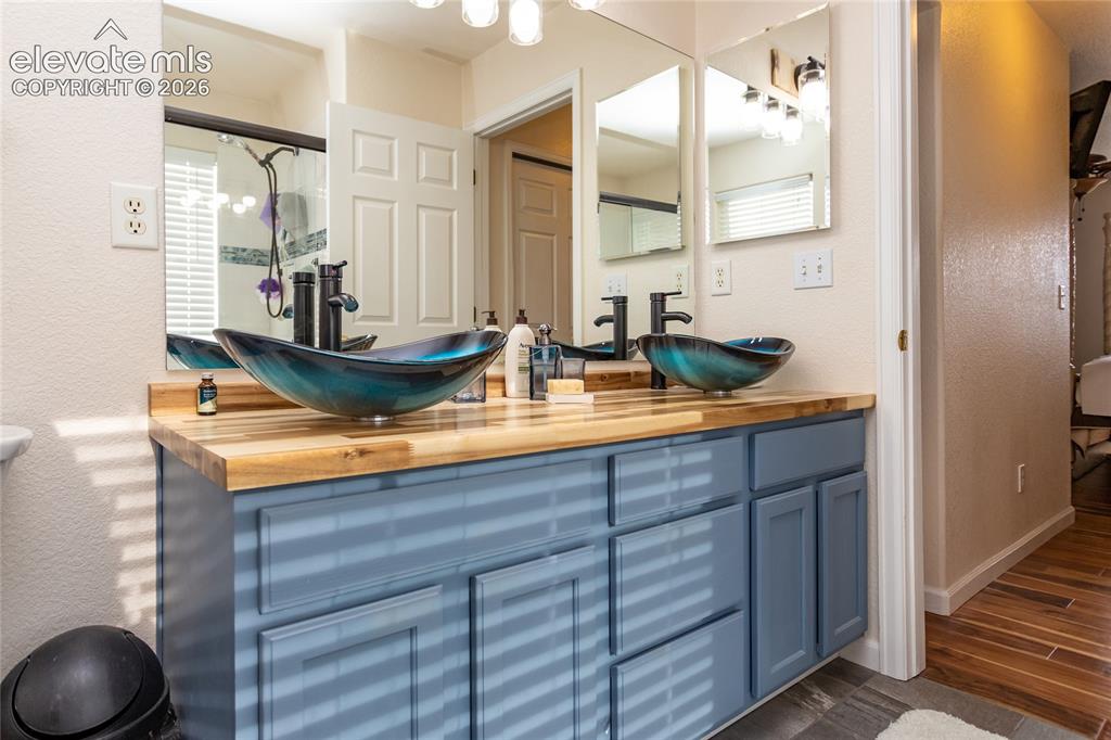 Image 29 of 44: These striking blue glass vessel sinks sit on a custom wood butcher-block c