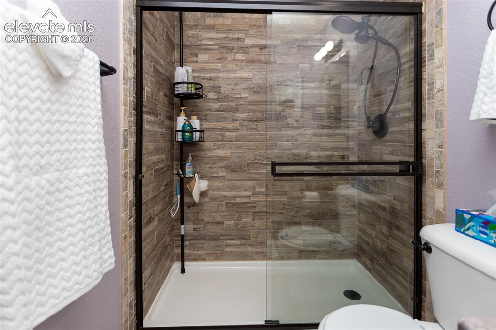 Image 36 of 44: Wood-look ceramic tile walls in the upper tub/shower enclosure provide a wa