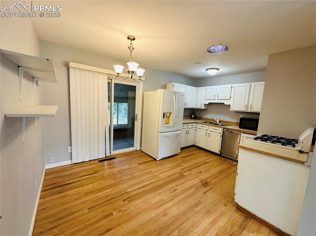 Image 12 of 17: Kitchen with white refrigerator with ice dispenser, stainless steel dishwas