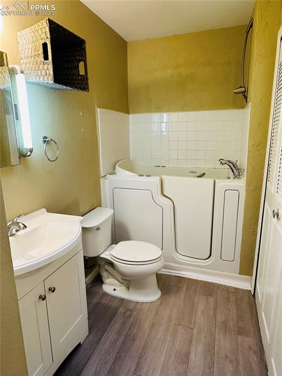 Image 13 of 17: Bathroom featuring vanity, wood finished floors, a garden tub, and a textur