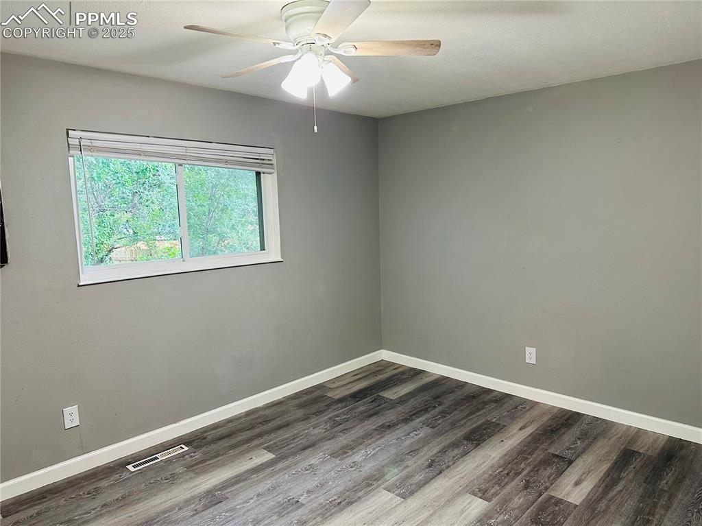 Image 7 of 17: Unfurnished room with dark wood-style floors and ceiling fan