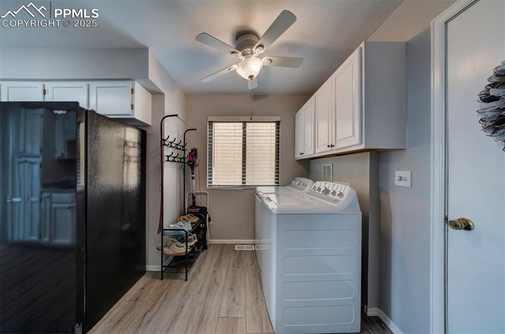 Image 18 of 44:  Main level Laundry area with light wood-type flooring, washer and clothes 