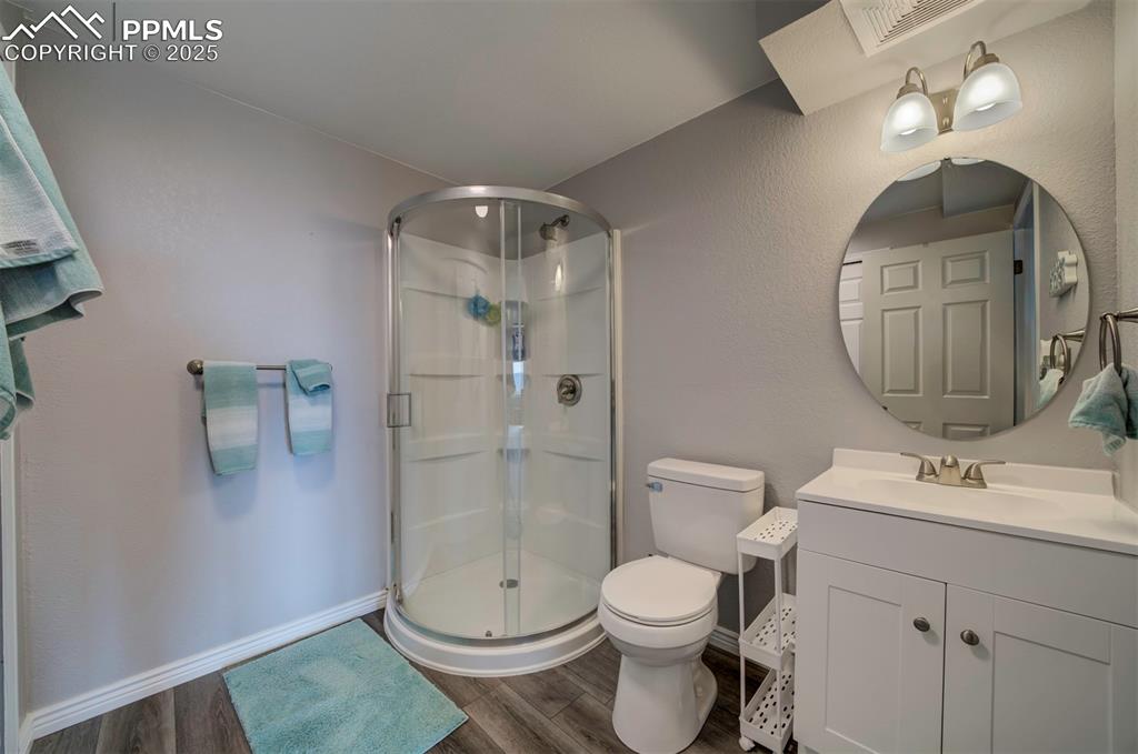 Image 32 of 44:  Basement Full bath with a stall shower, vanity, and dark wood finished flo