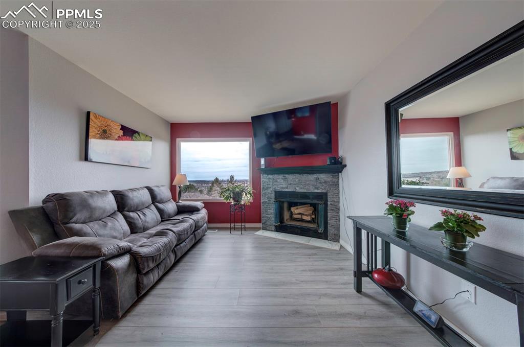 Image 6 of 44: Living area featuring a stone fireplace and light wood-style flooring