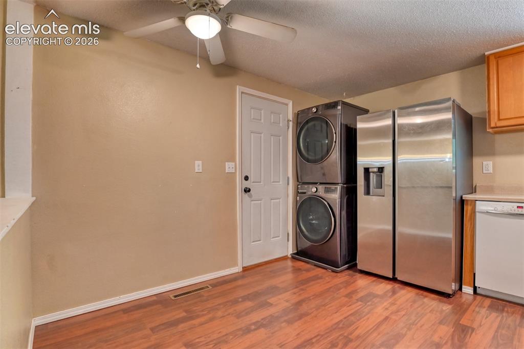 Image 11 of 35: Kitchen area with wood-finish flooring, light beige wall paint, white trim,