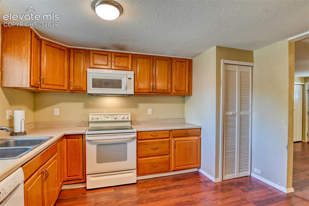 Image 12 of 35: Kitchen featuring wood cabinetry, laminate countertops, a double basin sink