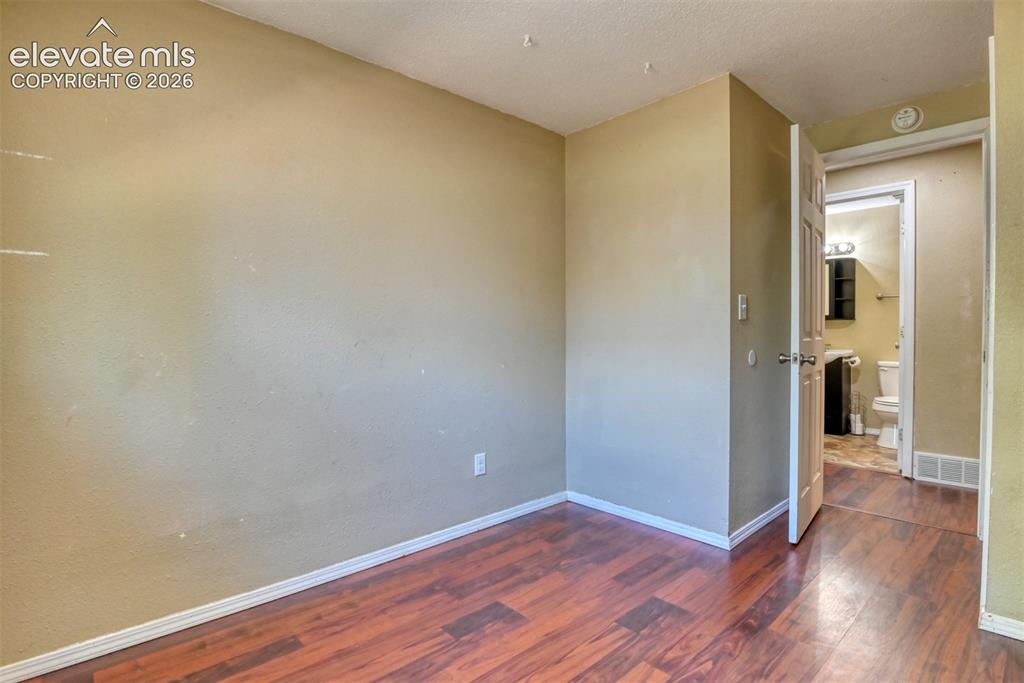 Image 17 of 35: Room featuring neutral-toned walls, wood-finish flooring, and white baseboa