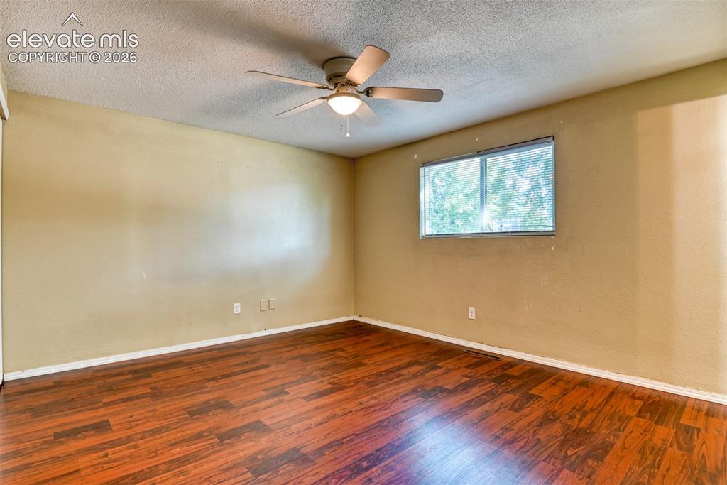 Image 24 of 35: Spacious room featuring wood-finish flooring, a ceiling fan with integrated