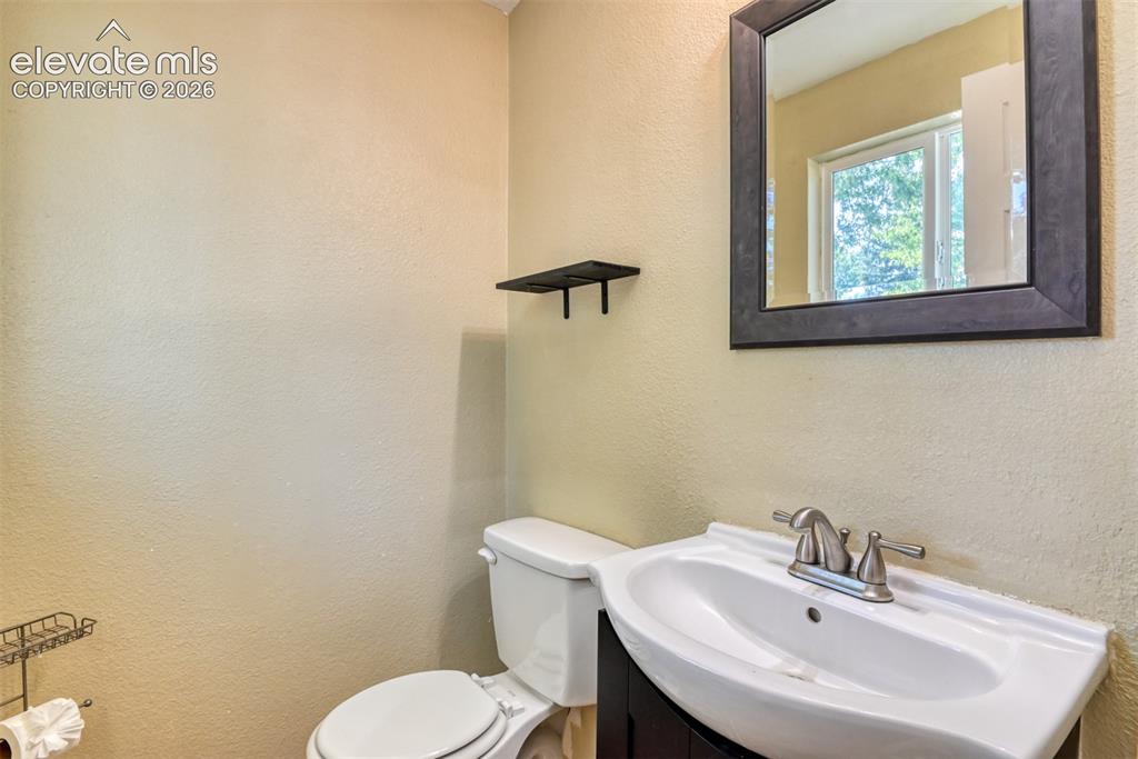 Image 28 of 35: Powder room featuring a dark wood-finish framed mirror, white ceramic sink 