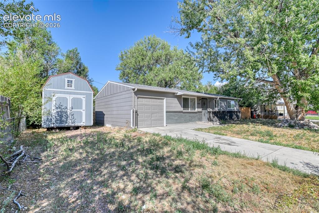 Image 3 of 35: Gray ranch-style home featuring an attached garage with a gray door, light 